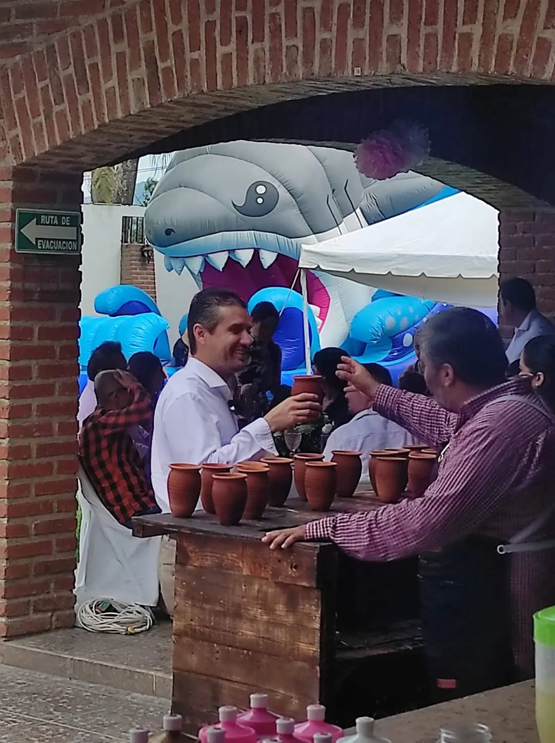 Invitados brindando con cantaritos frente a la barra Gran Alegre